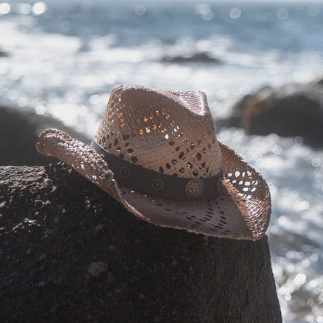 Straw hat on rocks at the beach.