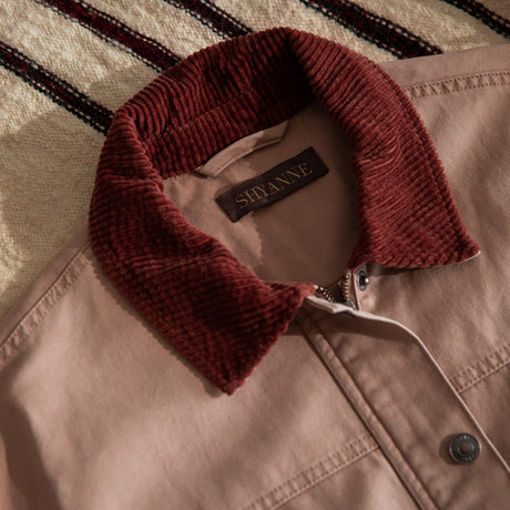 Close-up of a beige jacket with a deep burgundy corduroy collar.