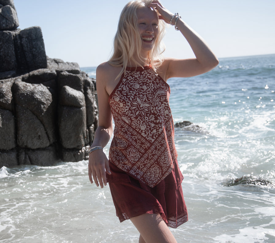 Woman at the beach wearing a red print halter top and  red skirt